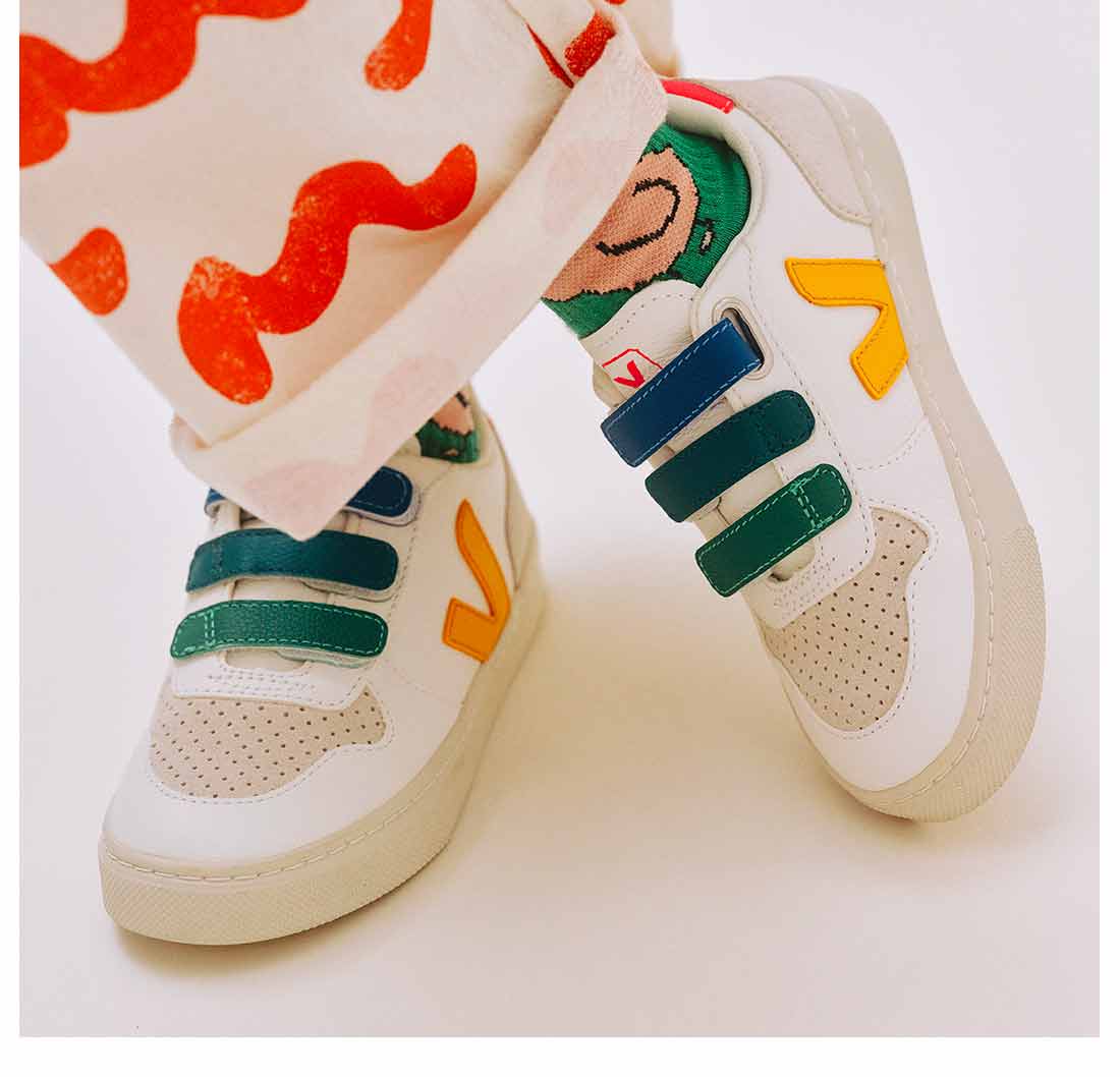 Focus on the feet of a child wearing V-10 chromefree multico white multico ouro trainers