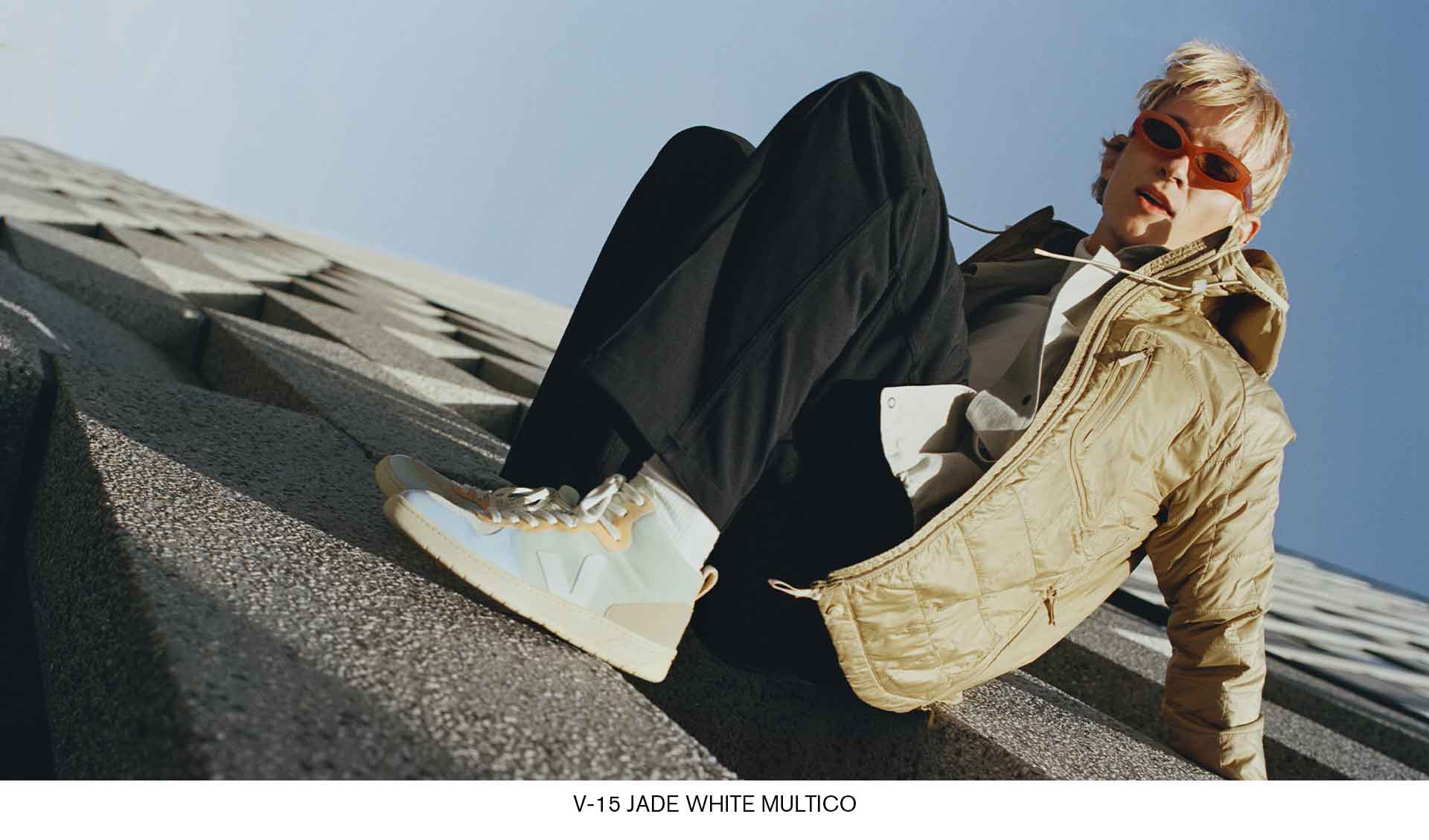 young man hanging on a wall with sneakers v-15 suede jade white multico