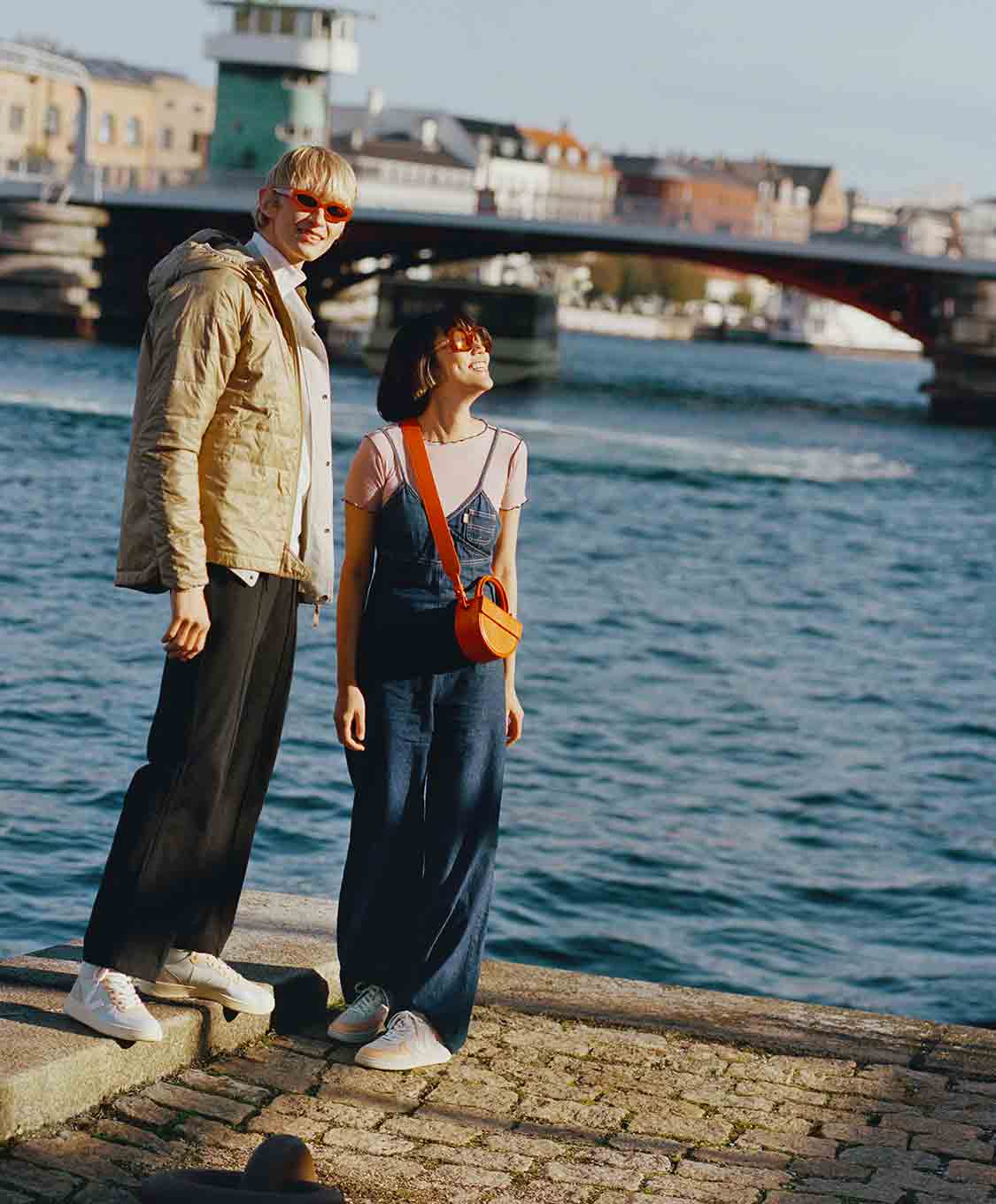 two people wearing VEJA sneakers near a port