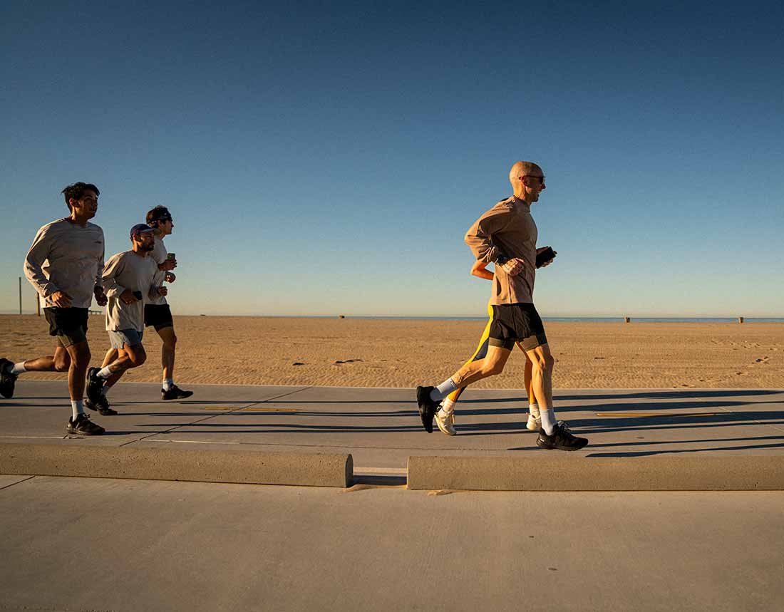 Group of people running on the boardwalk of Venice Beach